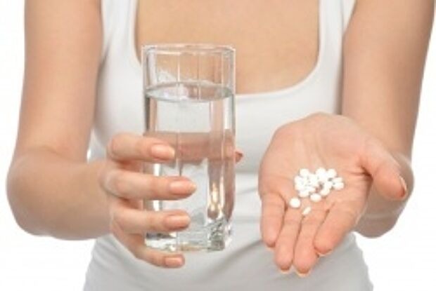 Junge Frau mit Tabletten und Wasserglas