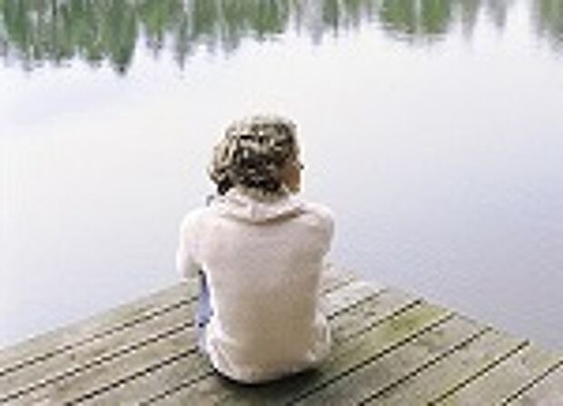 Eine Frau sitzt auf einem Steg am Wasser