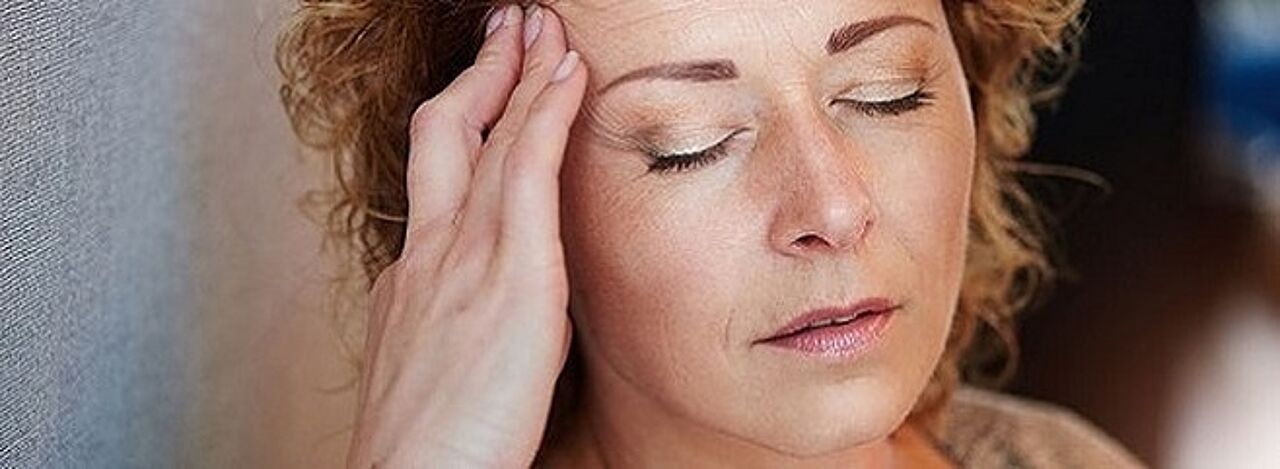 Frau mit Kopfschmerzen massiert sich die Schläfe