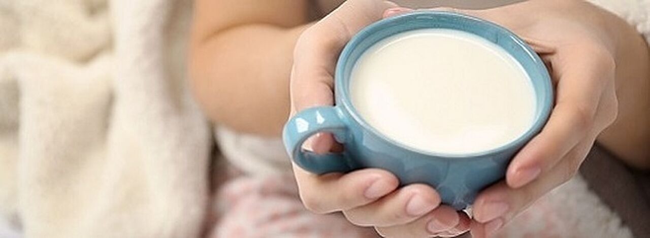 Frau hält Tasse mit warmer Milch in der Hand