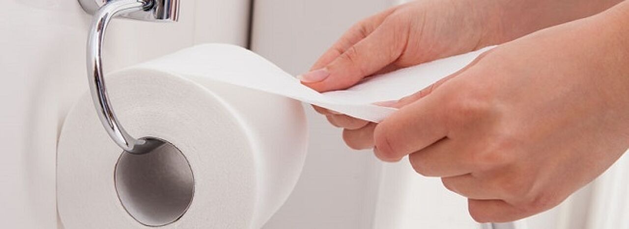 Frau rollt Toilettenpapier ab