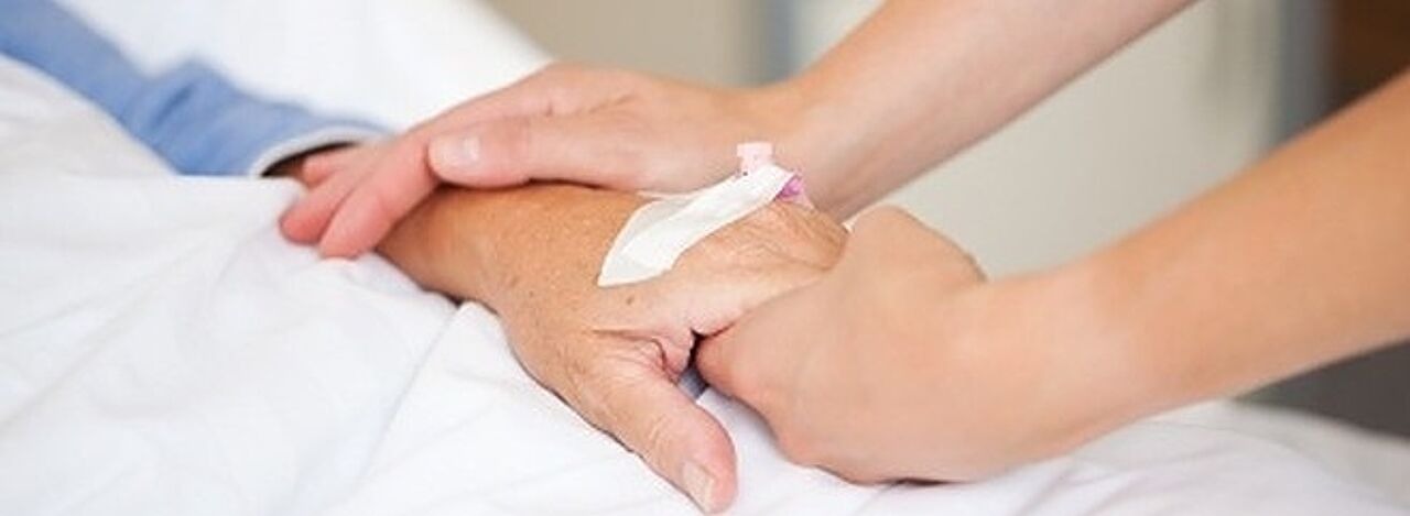 Ärztin hält älterer Patientin die Hand