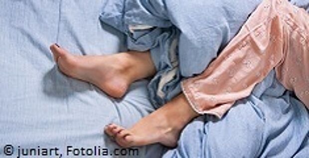 Frau im Bett mit unruhigen Beinen